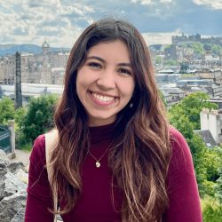 Picture of Mariana Rozo-Paz, the Youth4OurDataFuture Lead smiling while wearing a red sweater in front of a city landscape